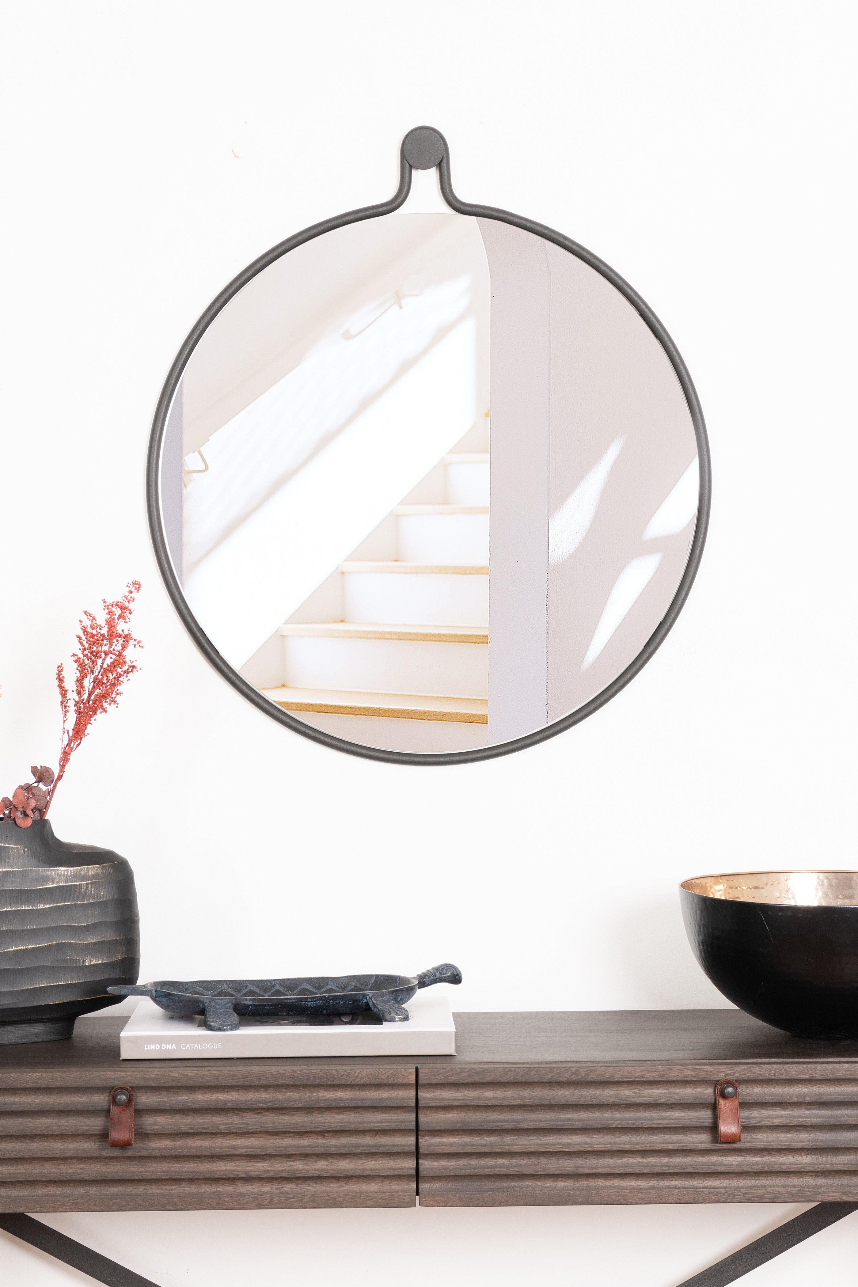 Elegant Brussels Round Mirror with a unique teardrop design, featuring a steel frame and natural leather strap.