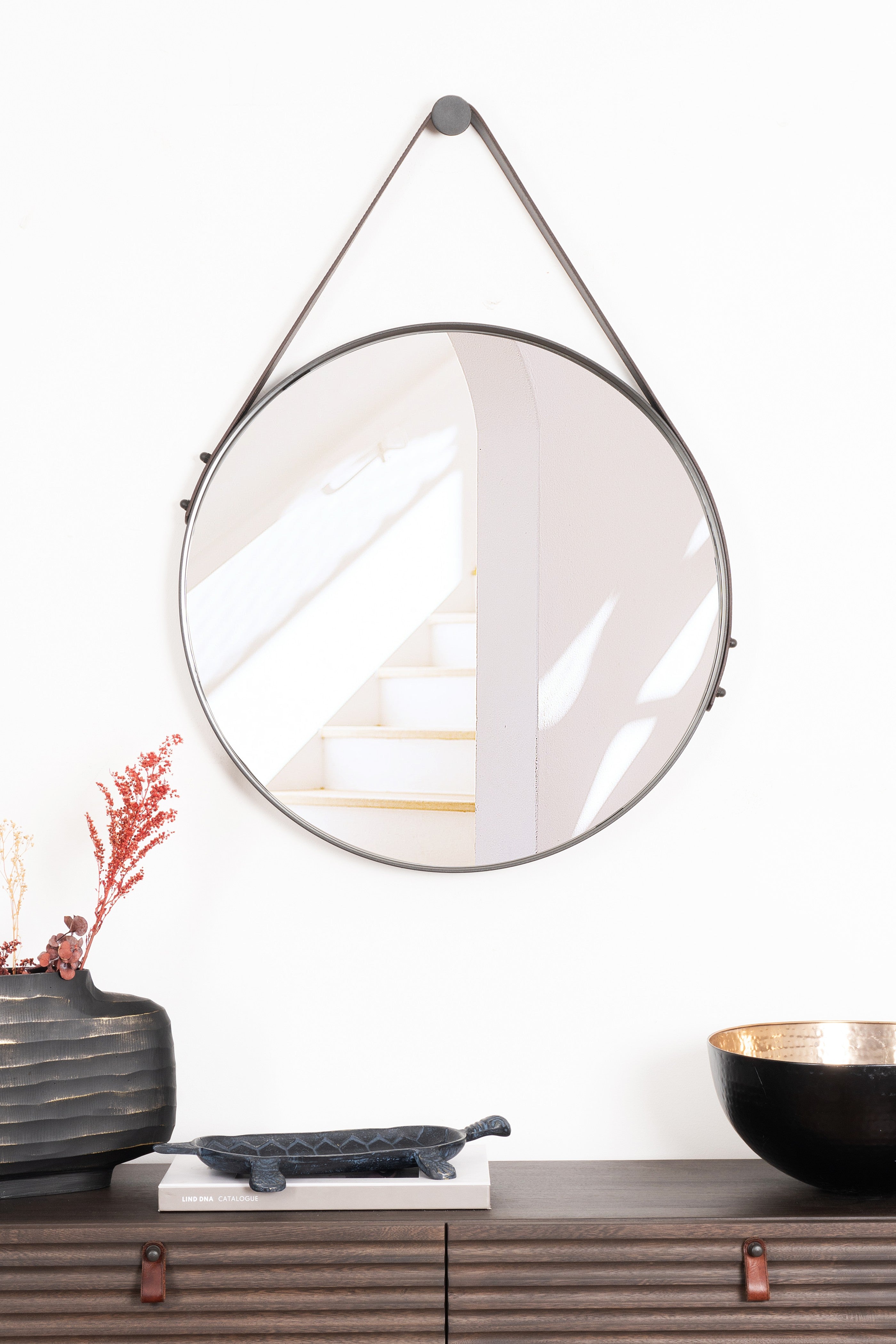 Sleek round Boston Mirror with a sturdy steel frame and elegant leather strap, perfect for adding modern charm to any room.